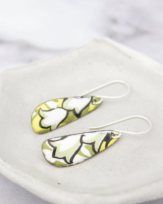A pair of earrings with a green and white floral pattern on a white plate.