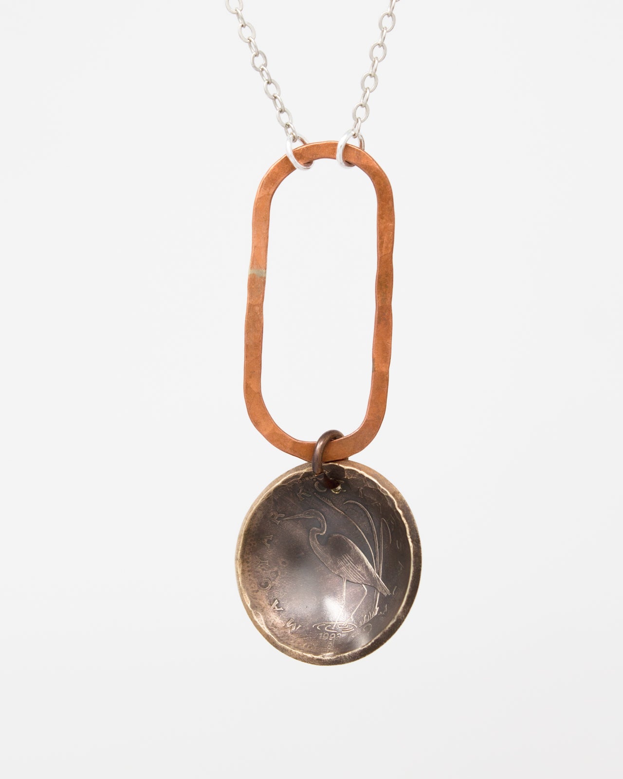 A necklace with a circular pendant featuring a design, hanging from a chain.