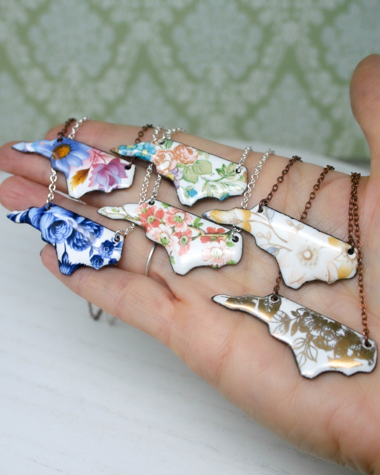 a person's hand holding a bunch of necklaces