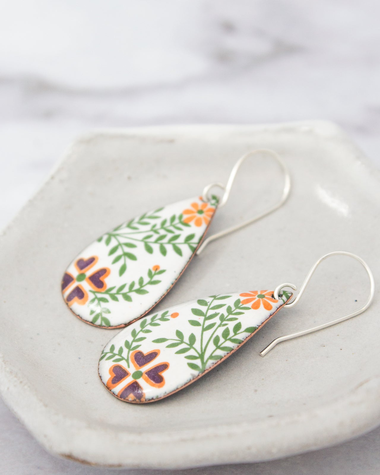 A pair of earrings with a floral design on a white plate.