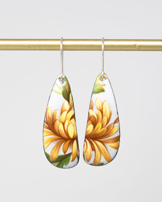 A pair of earrings with a floral design, featuring yellow flowers on a white background.