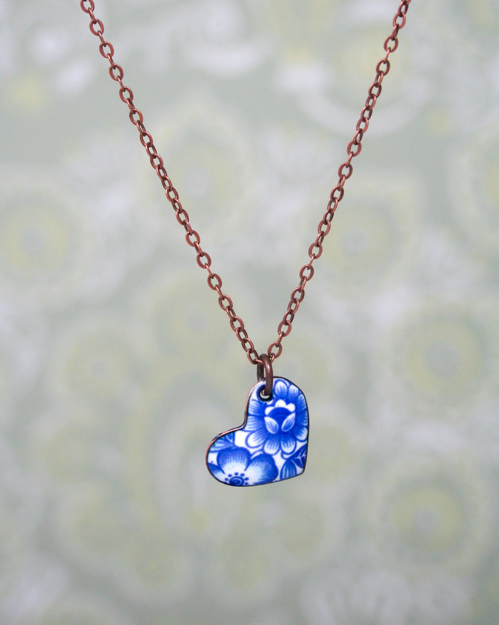 a necklace with a blue heart and flowers on it