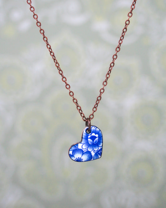 a necklace with a blue heart and flowers on it