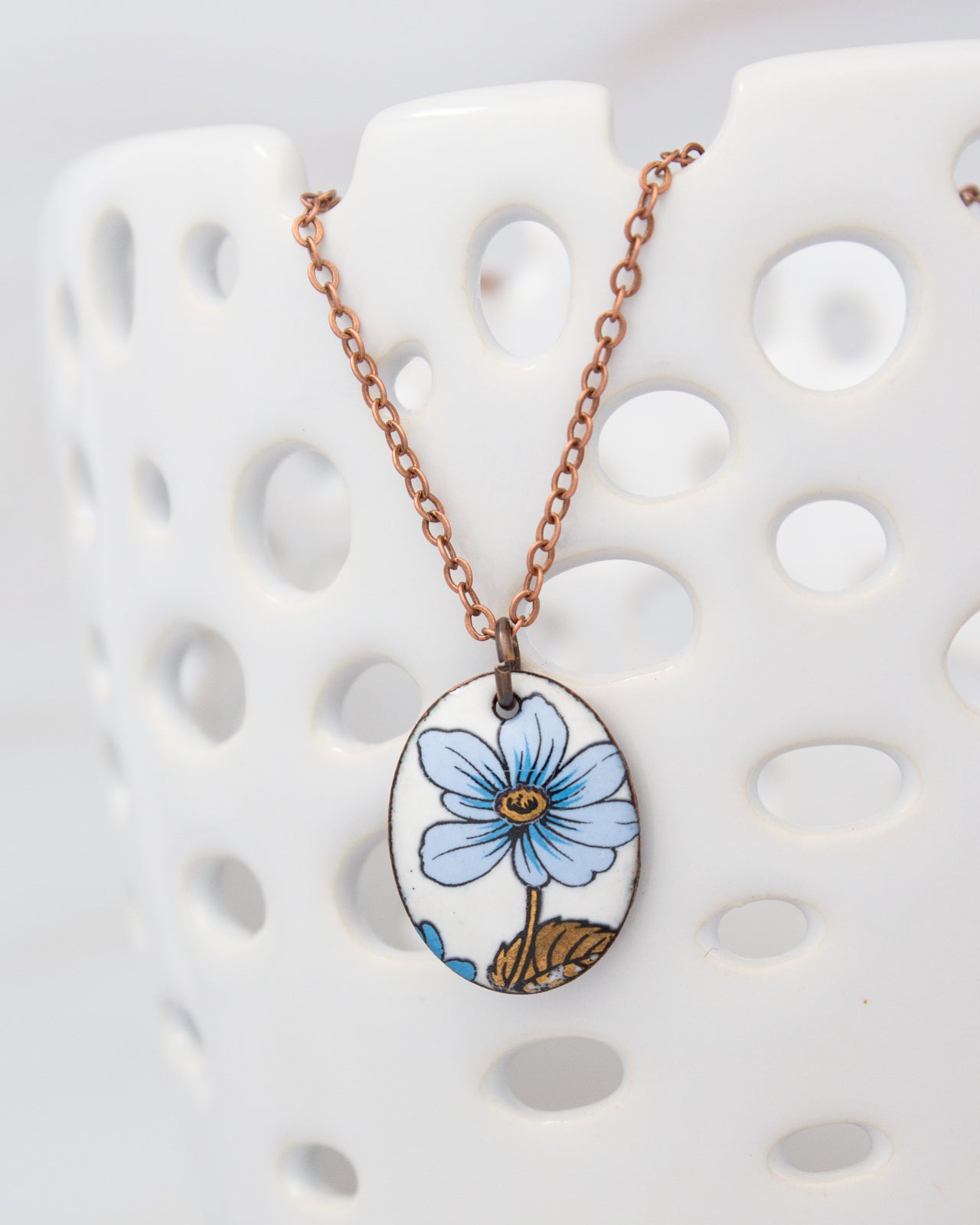 A necklace with a pendant featuring a blue flower design.