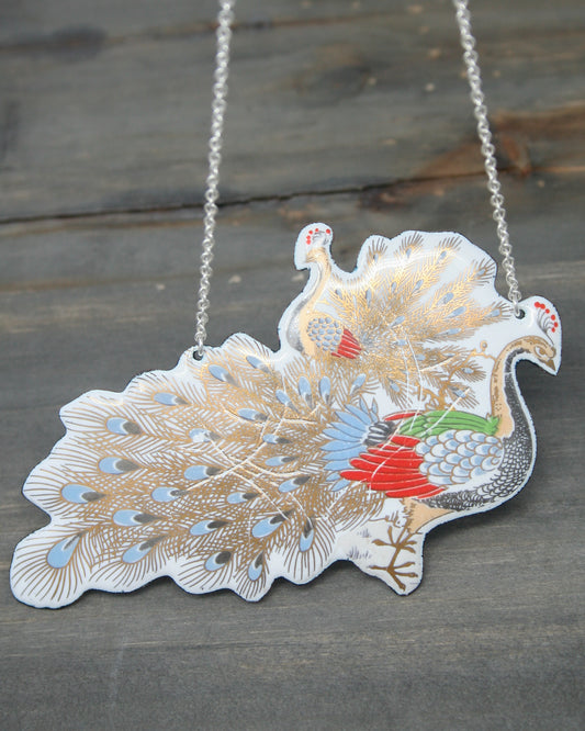 a silver necklace with a peacock on it