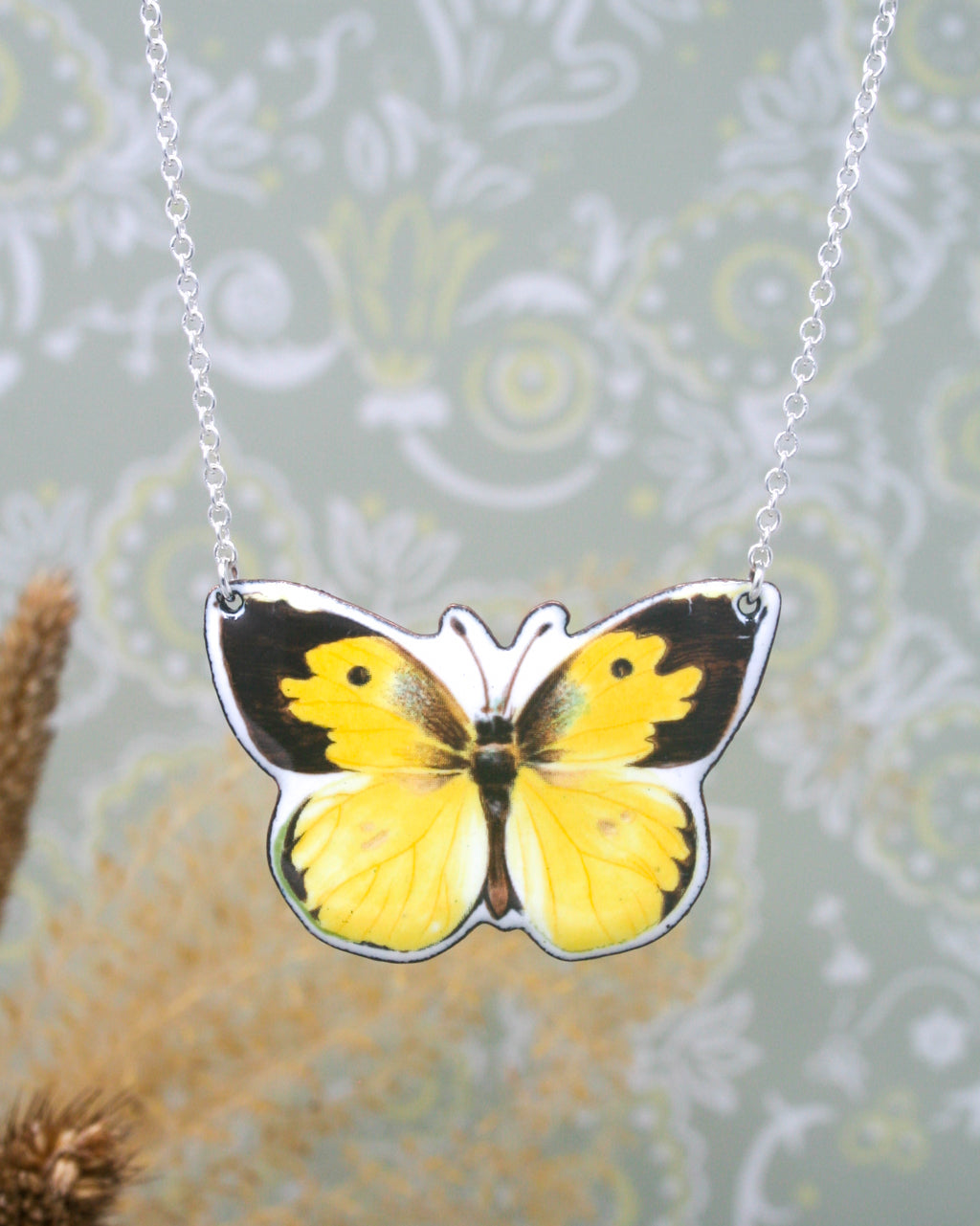 a yellow and black butterfly on a silver chain