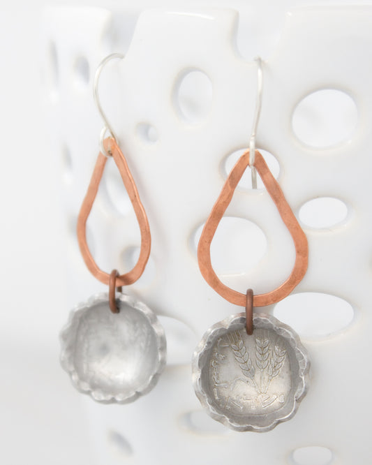 A pair of earrings with a metal pendant and a metal ring hanging from it, set against a white background.