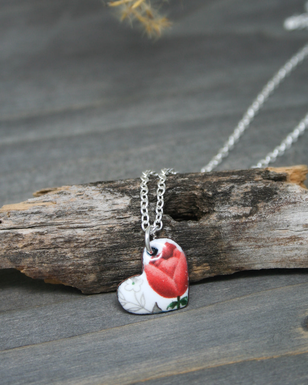 a red and white bird is sitting on a piece of wood