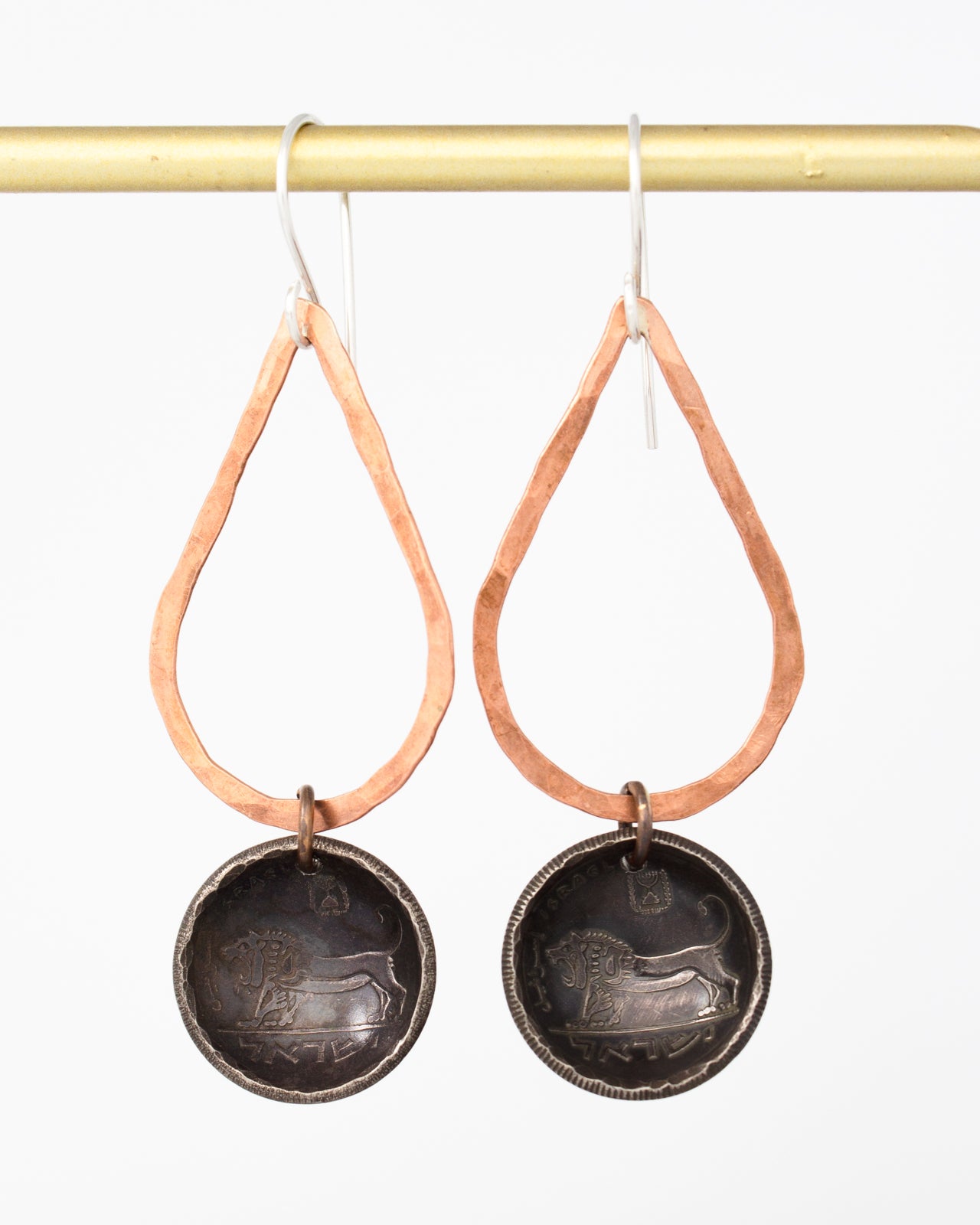 A pair of earrings with a copper-colored metal frame and a round metal pendant featuring a lion design.