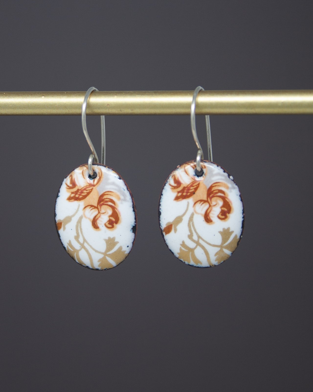 A pair of earrings with a floral design on a dark background.