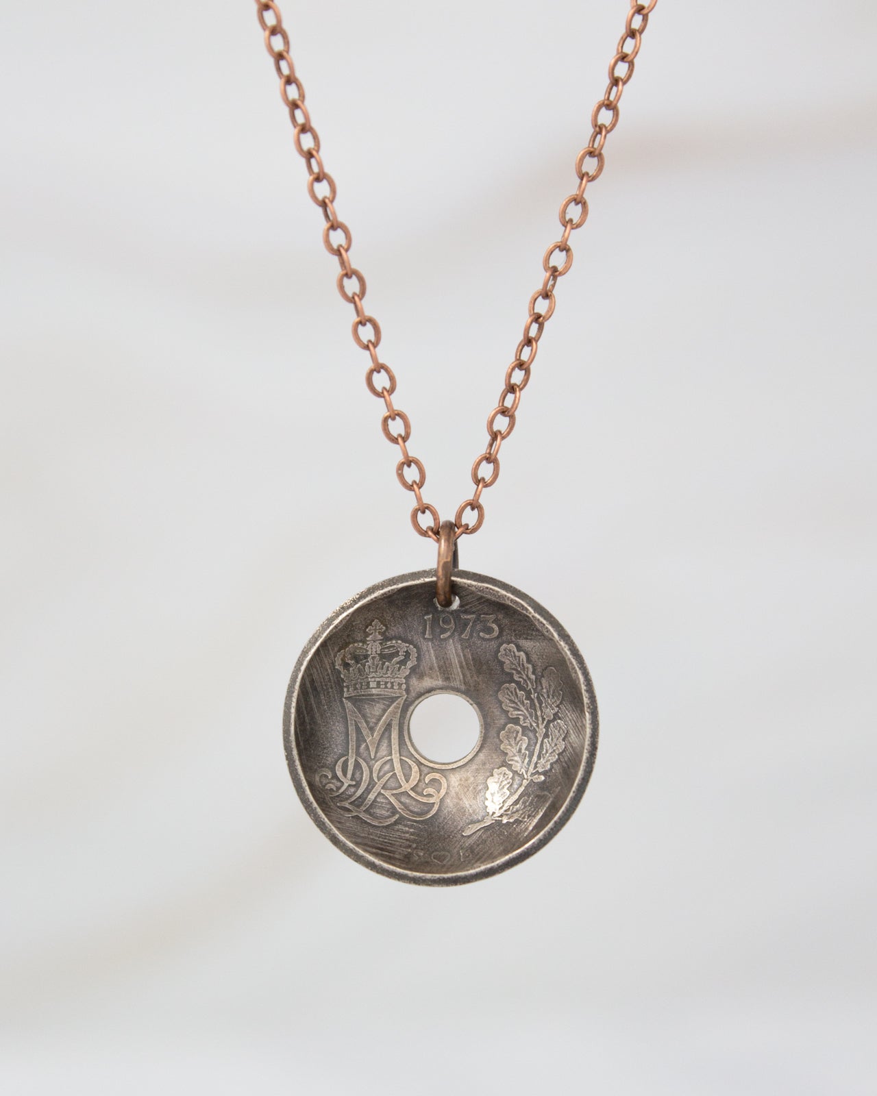 A necklace with a circular pendant featuring a coin design.