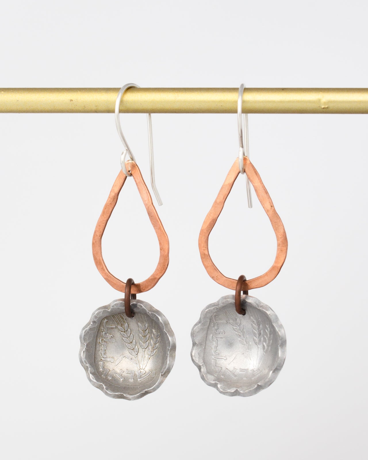 A pair of earrings with a metal frame and a metal pendant hanging from a gold hook.