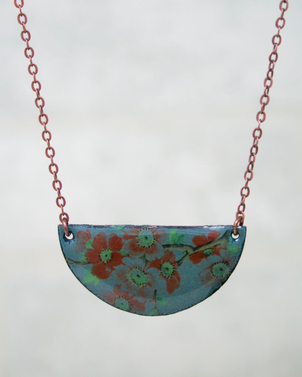 A necklace with a blue pendant featuring a floral design.