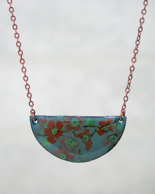 A necklace with a blue pendant featuring a floral design.