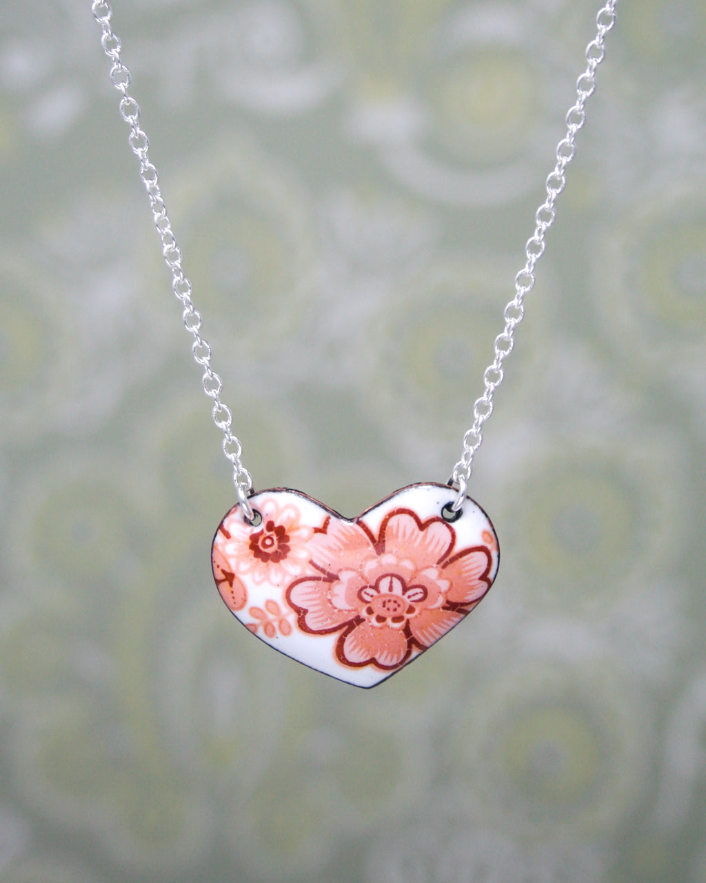 a heart shaped necklace with a flower on it