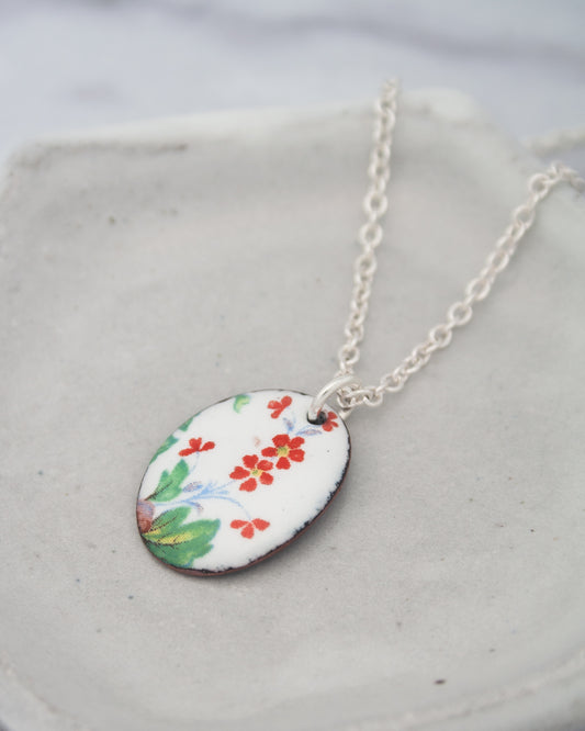A necklace with a pendant featuring a floral design in red, green, and yellow colors.