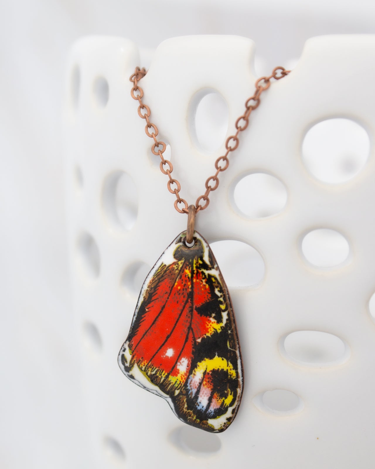 A necklace with a pendant featuring a colorful butterfly wing design.