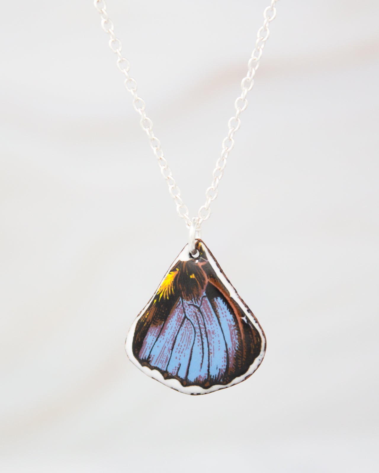 A necklace with a pendant featuring a colorful butterfly wing design.