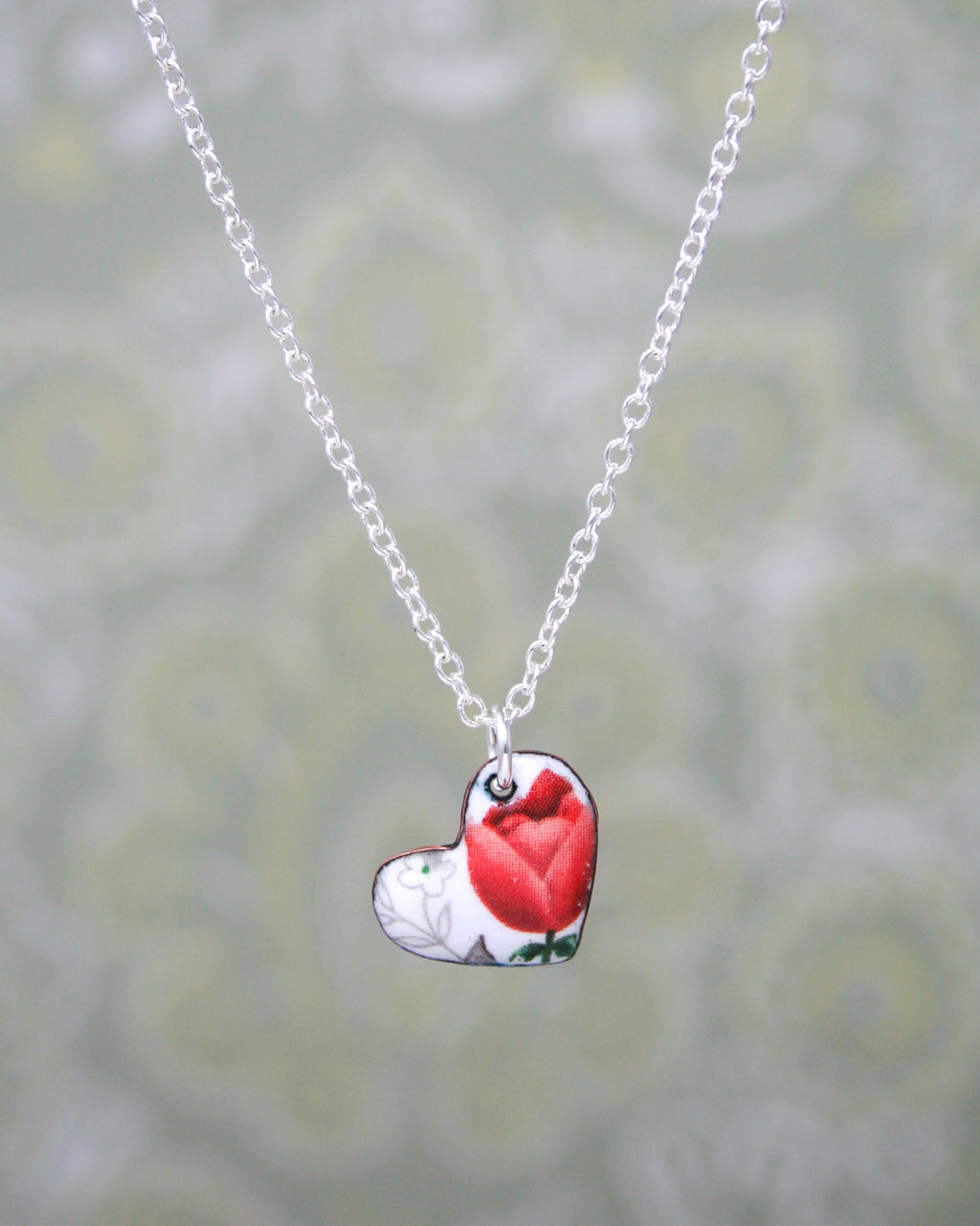 a red and white heart pendant on a silver chain