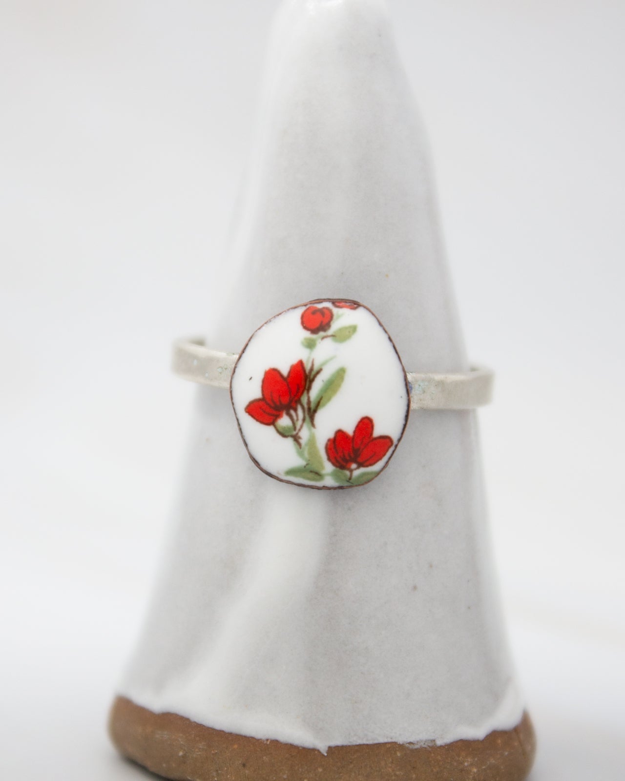 A white ceramic ring stand with a round, floral-patterned design on it.