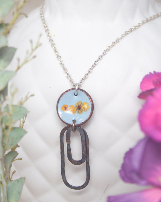 A necklace with a circular pendant featuring a floral design, hanging from a chain.