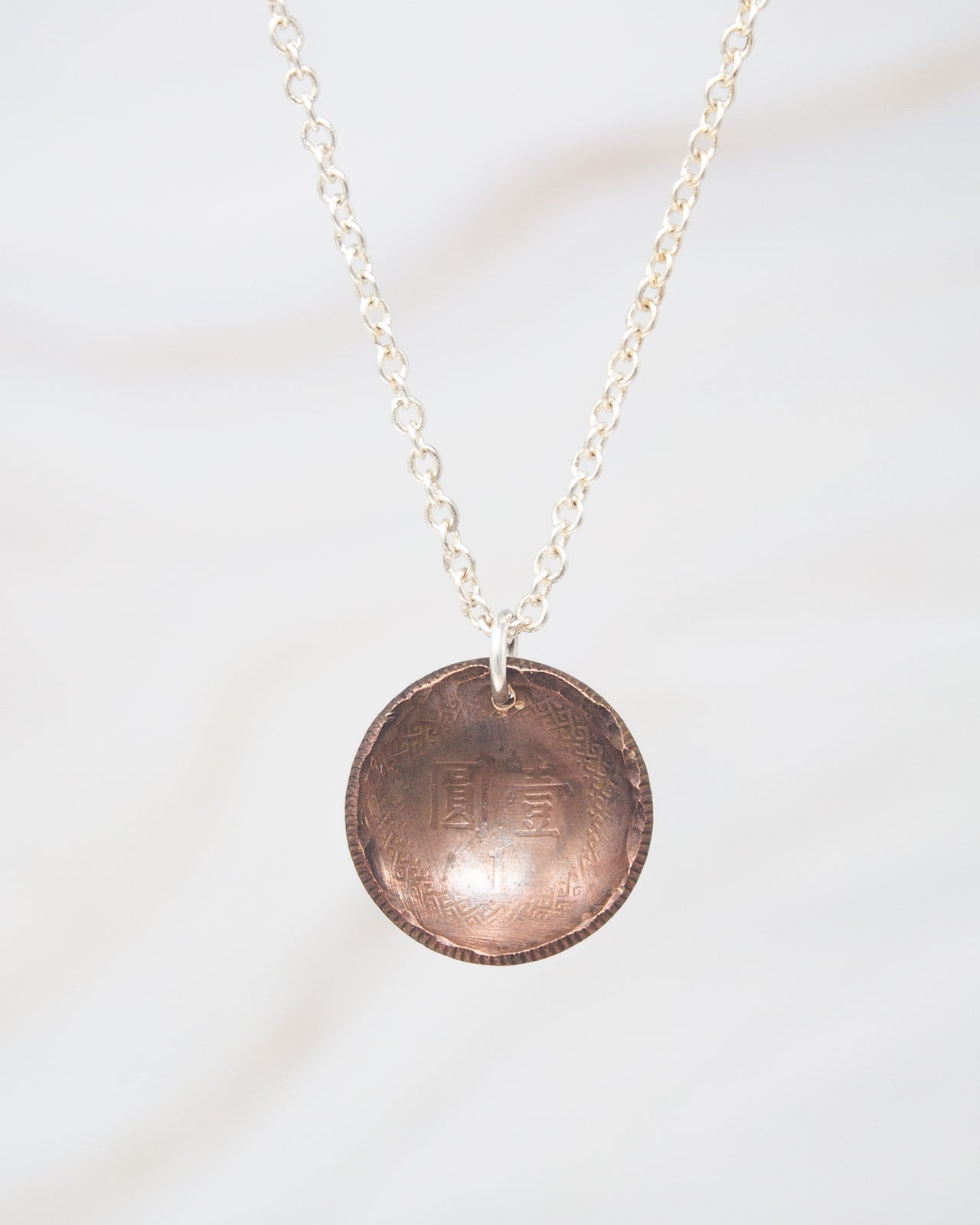 A necklace with a round pendant featuring an engraved design.