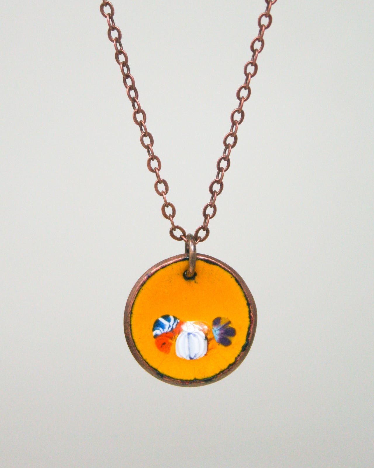 A necklace with a circular pendant featuring a vibrant design of three colorful flowers.