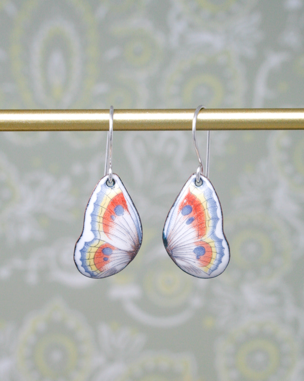 a pair of butterfly shaped earrings hanging from a rod