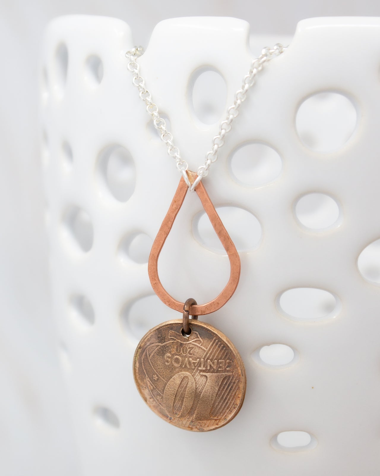 A necklace with a pendant featuring a coin-like design and a chain.