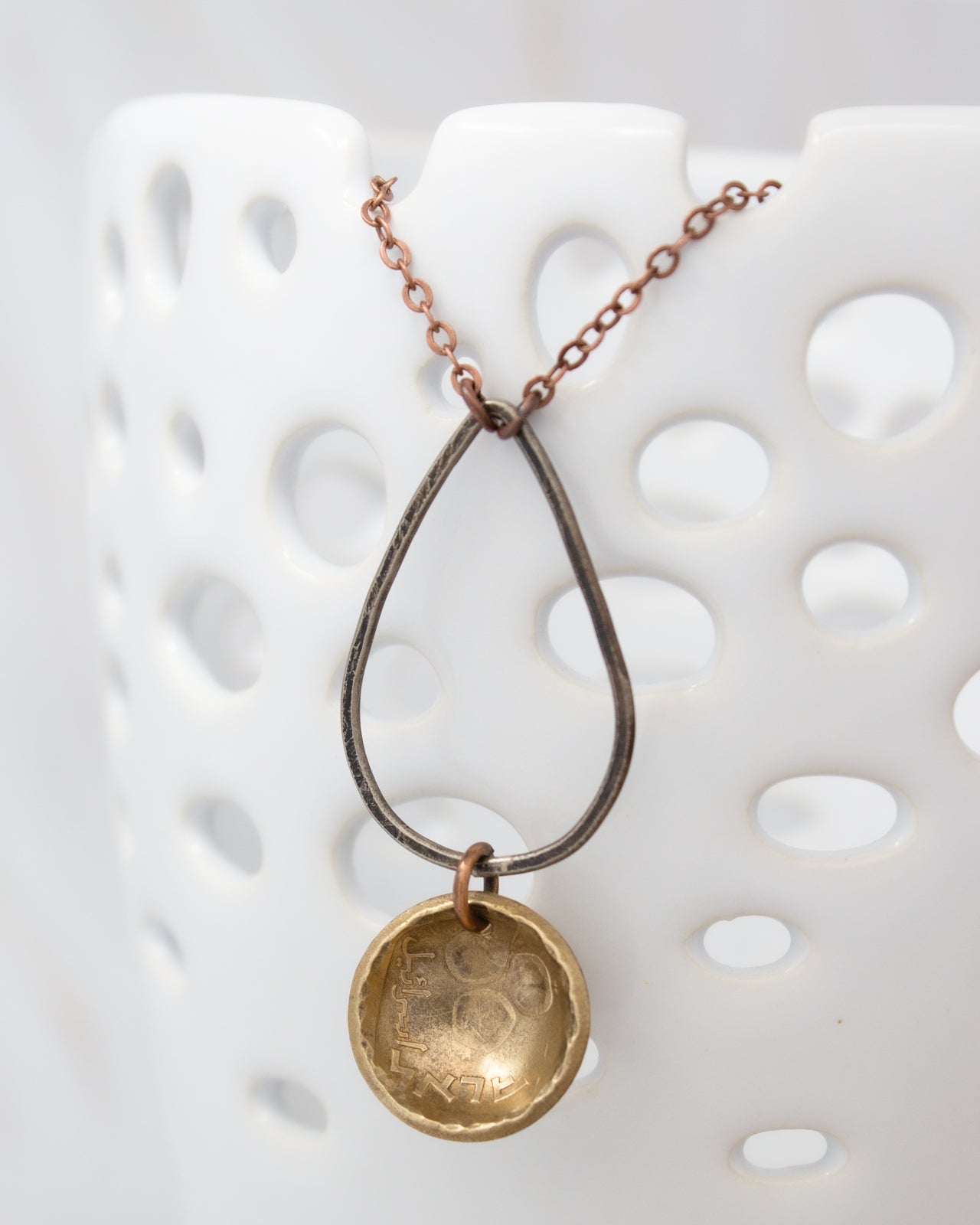 A necklace with a pendant featuring a small, round, metallic object hanging from a chain.