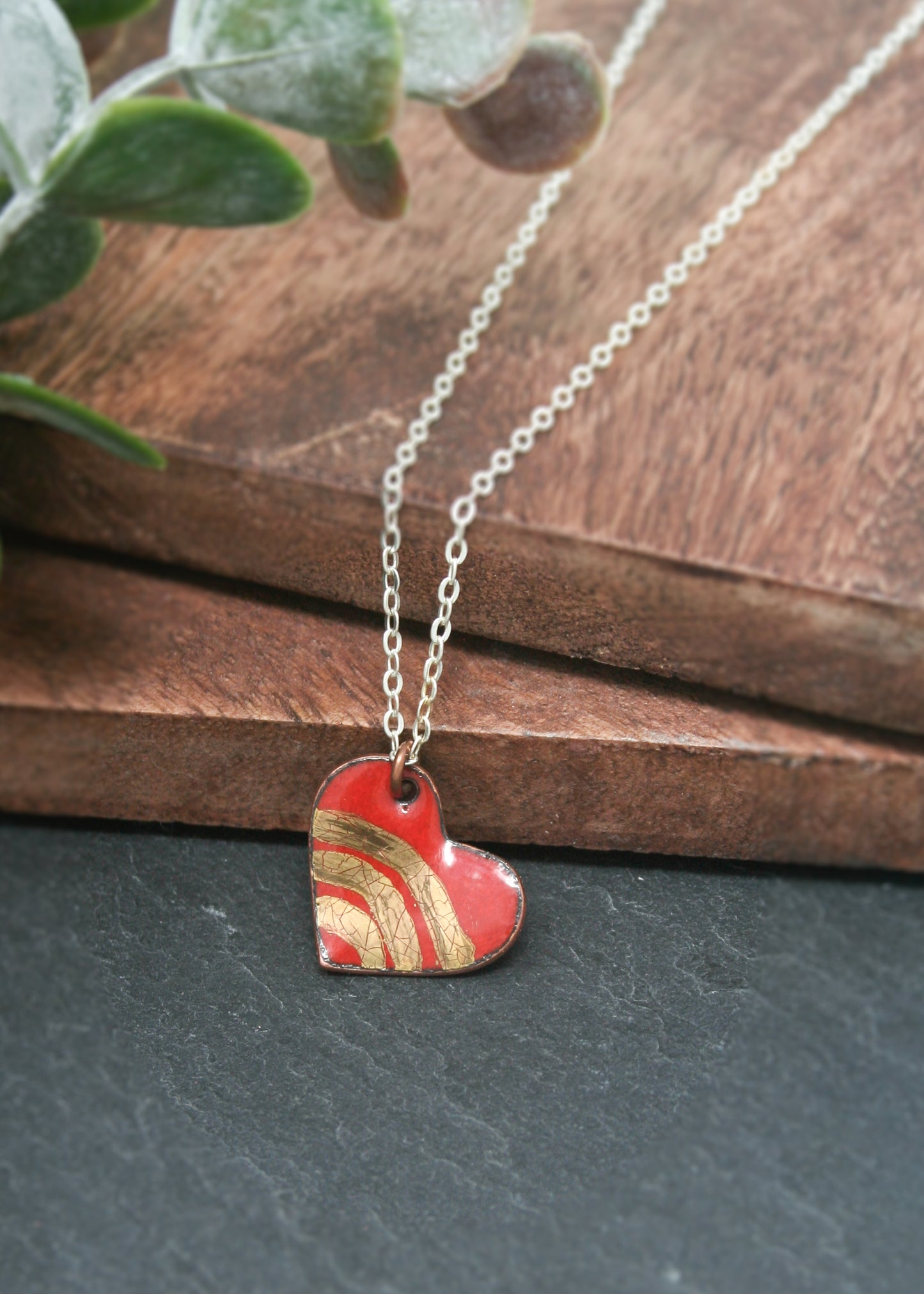 a red heart shaped pendant sitting on top of a wooden table