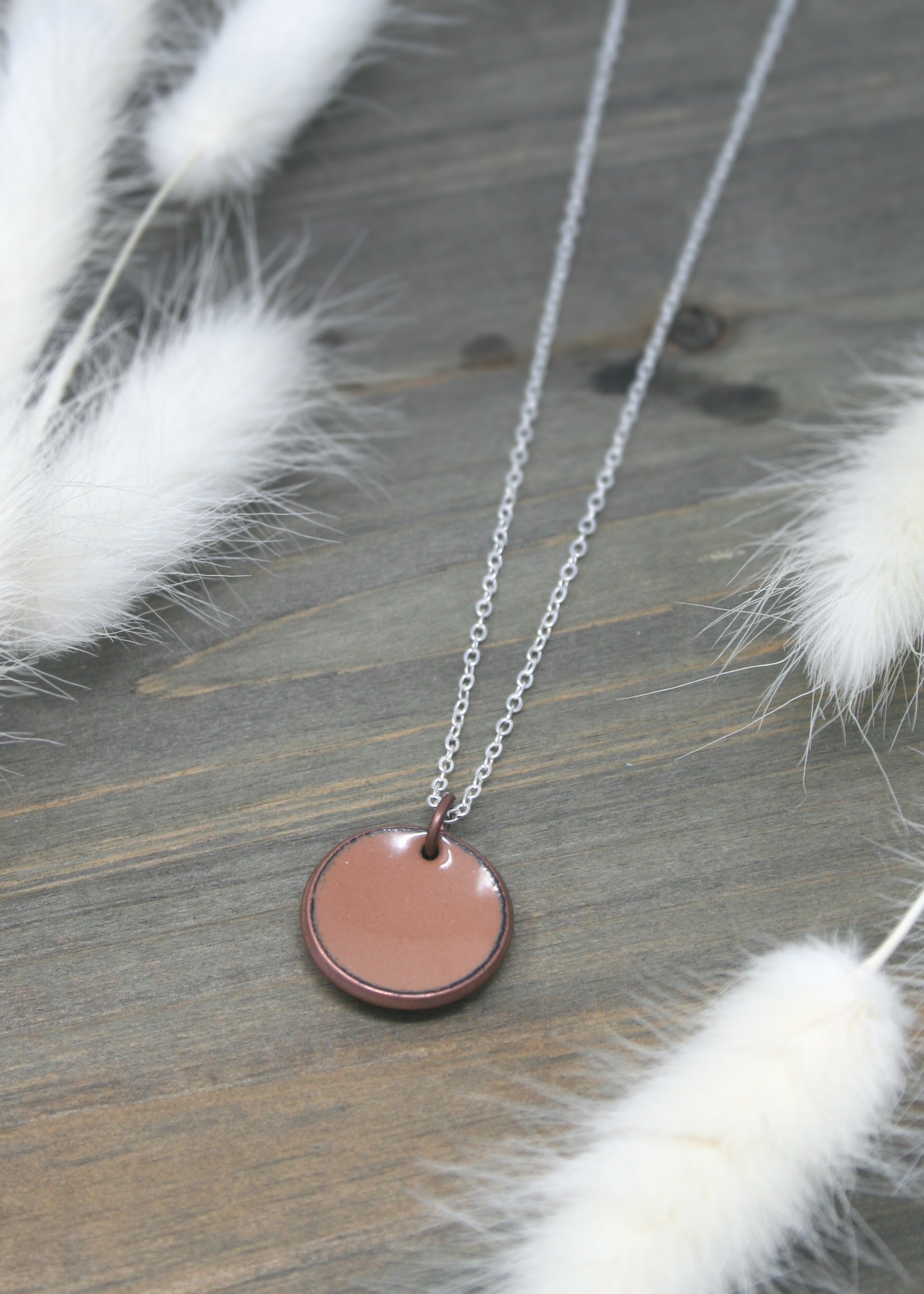a necklace with a pink disc on a chain