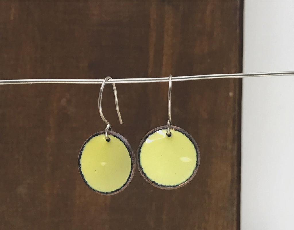 a pair of yellow earrings hanging from a clothes line