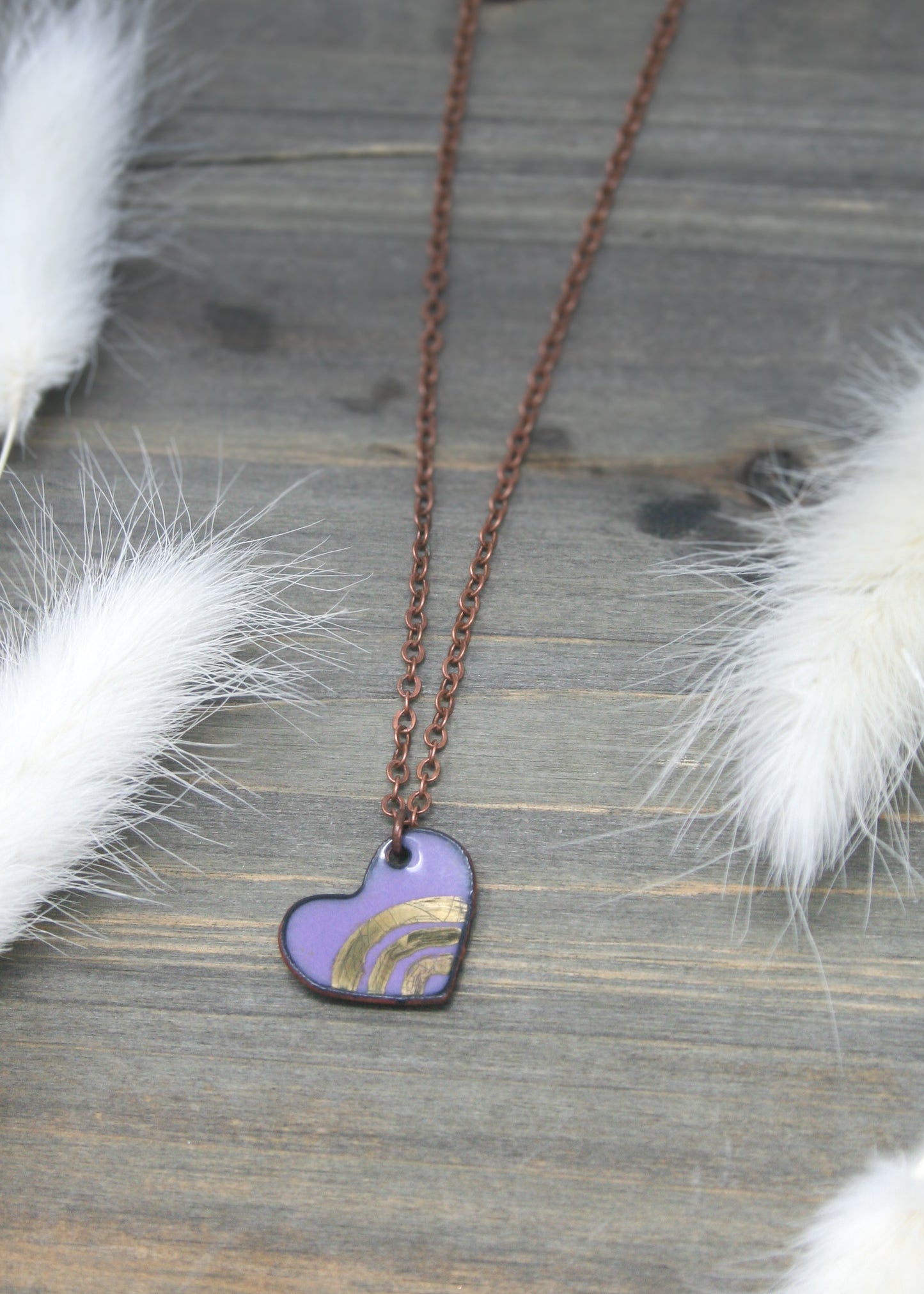 a necklace with a heart shaped pendant on a wooden surface