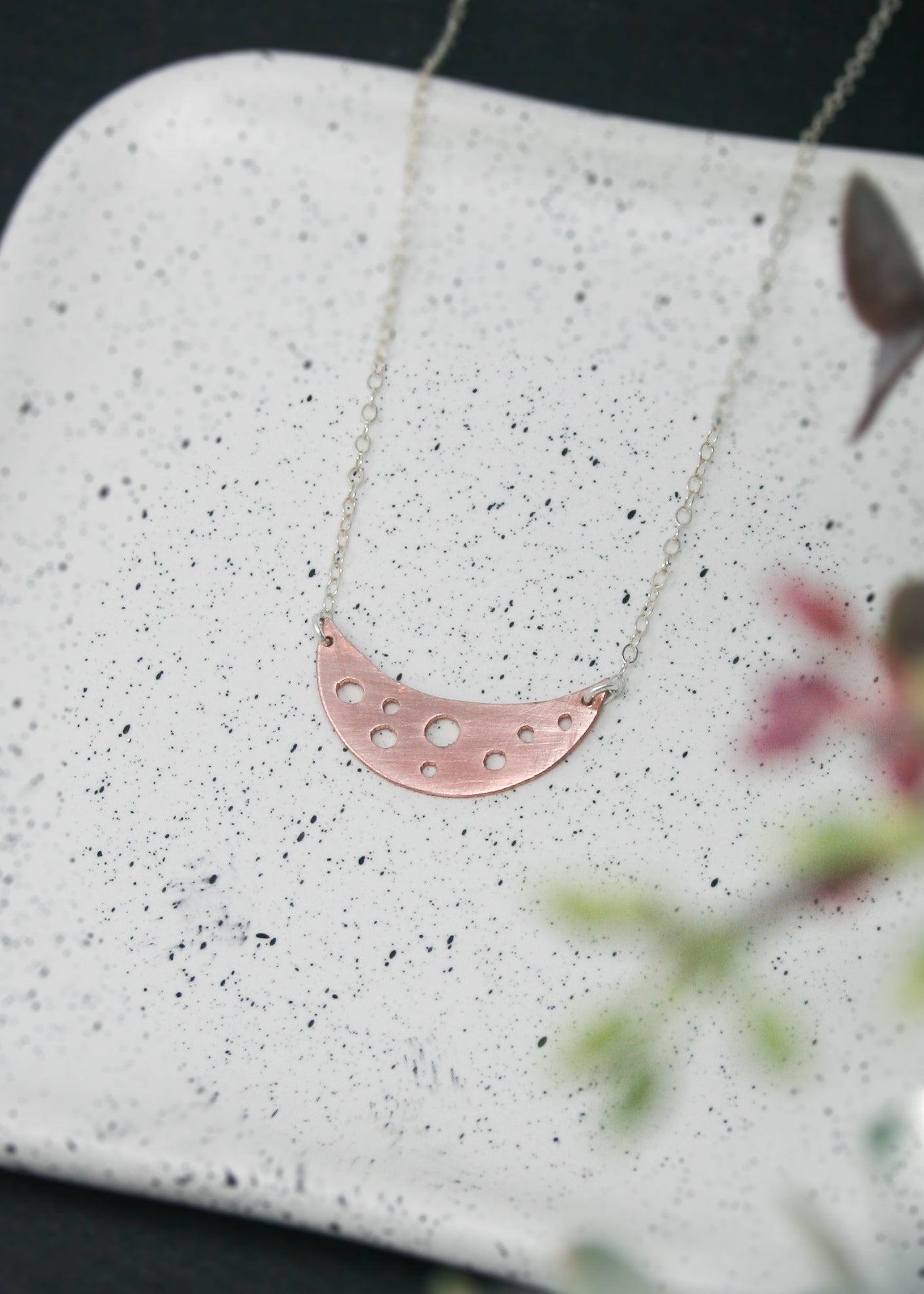 a pink crescent necklace on a white plate