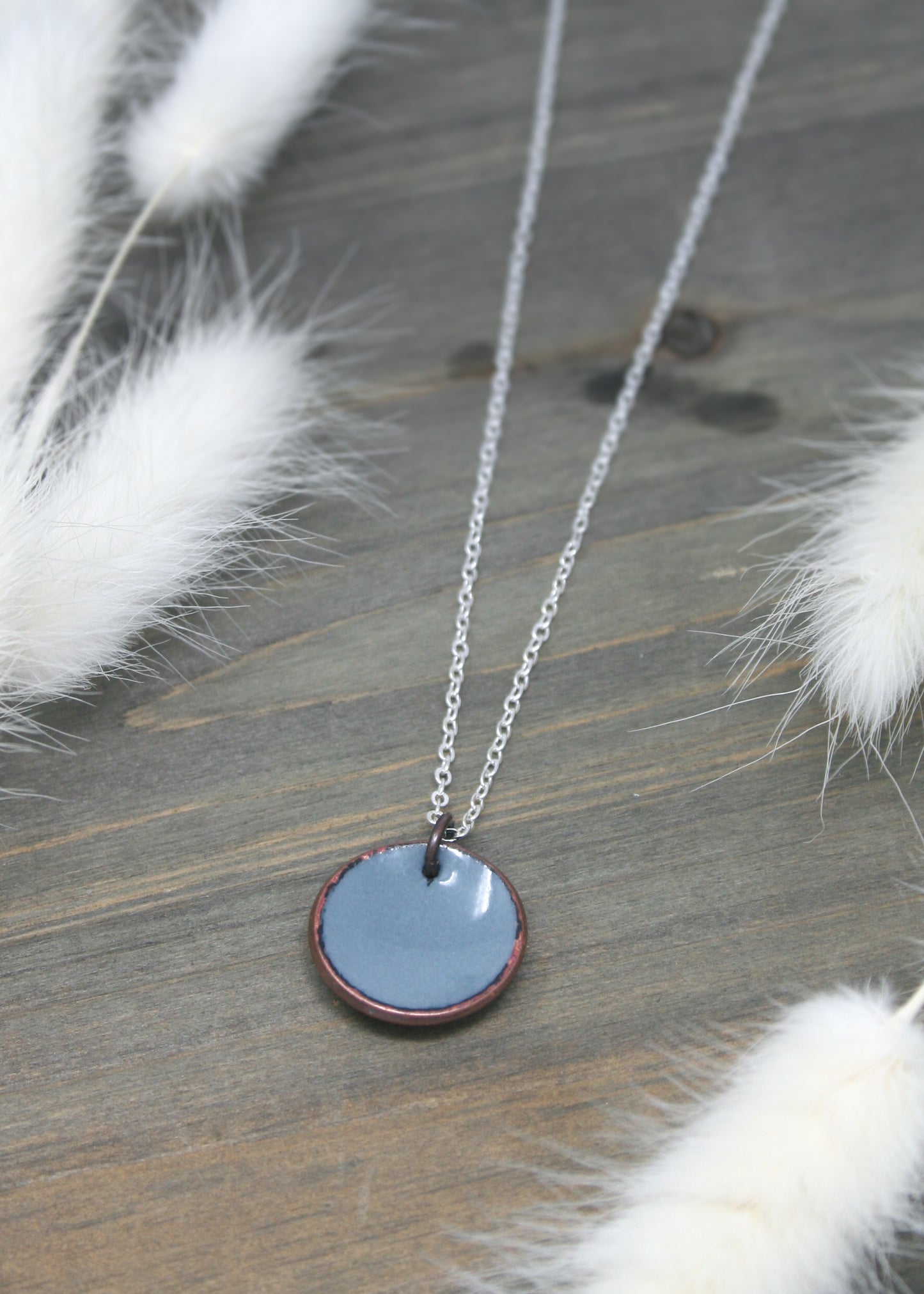 a necklace with a blue disc hanging from a chain