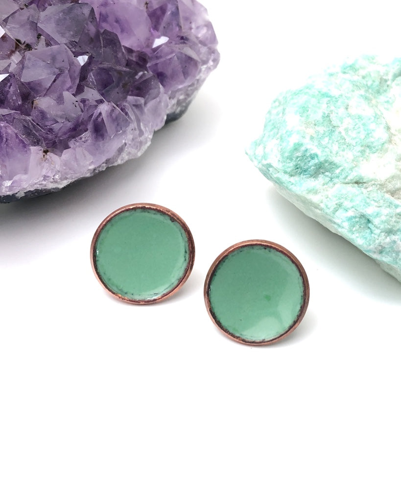 a pair of green earrings sitting on top of a rock
