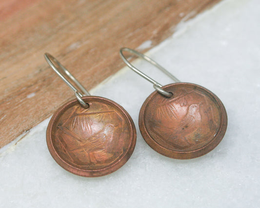 a pair of earrings with a picture of a bird on them
