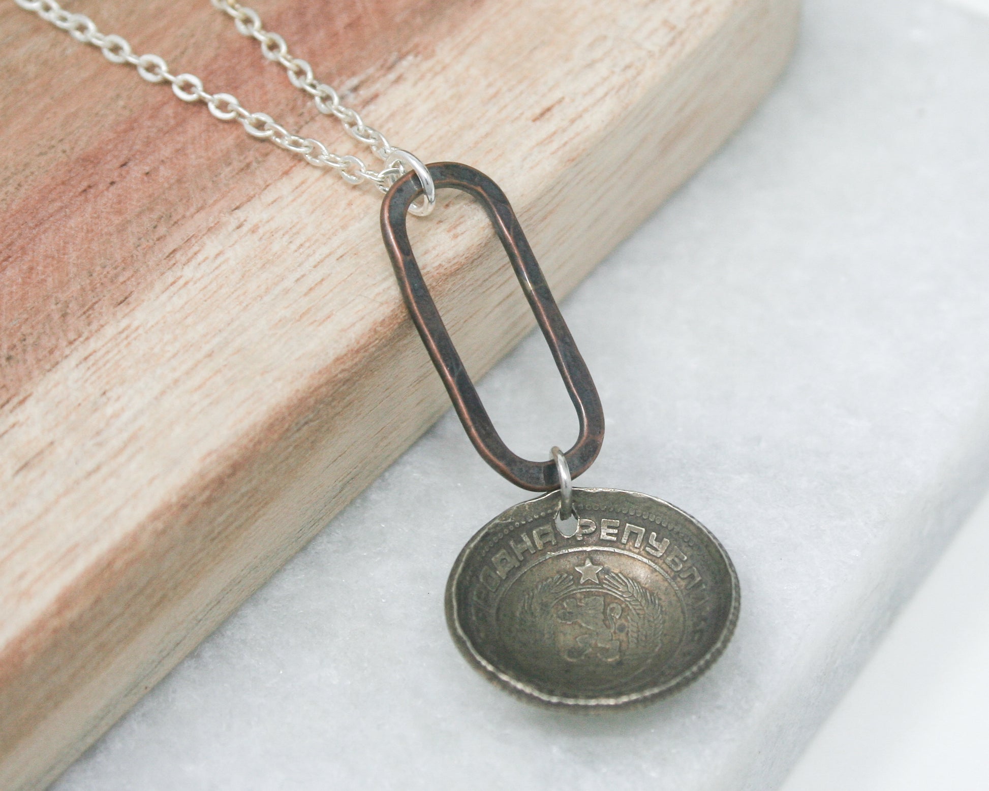a necklace with a coin hanging from it