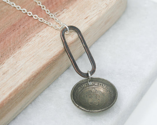 a necklace with a coin hanging from it