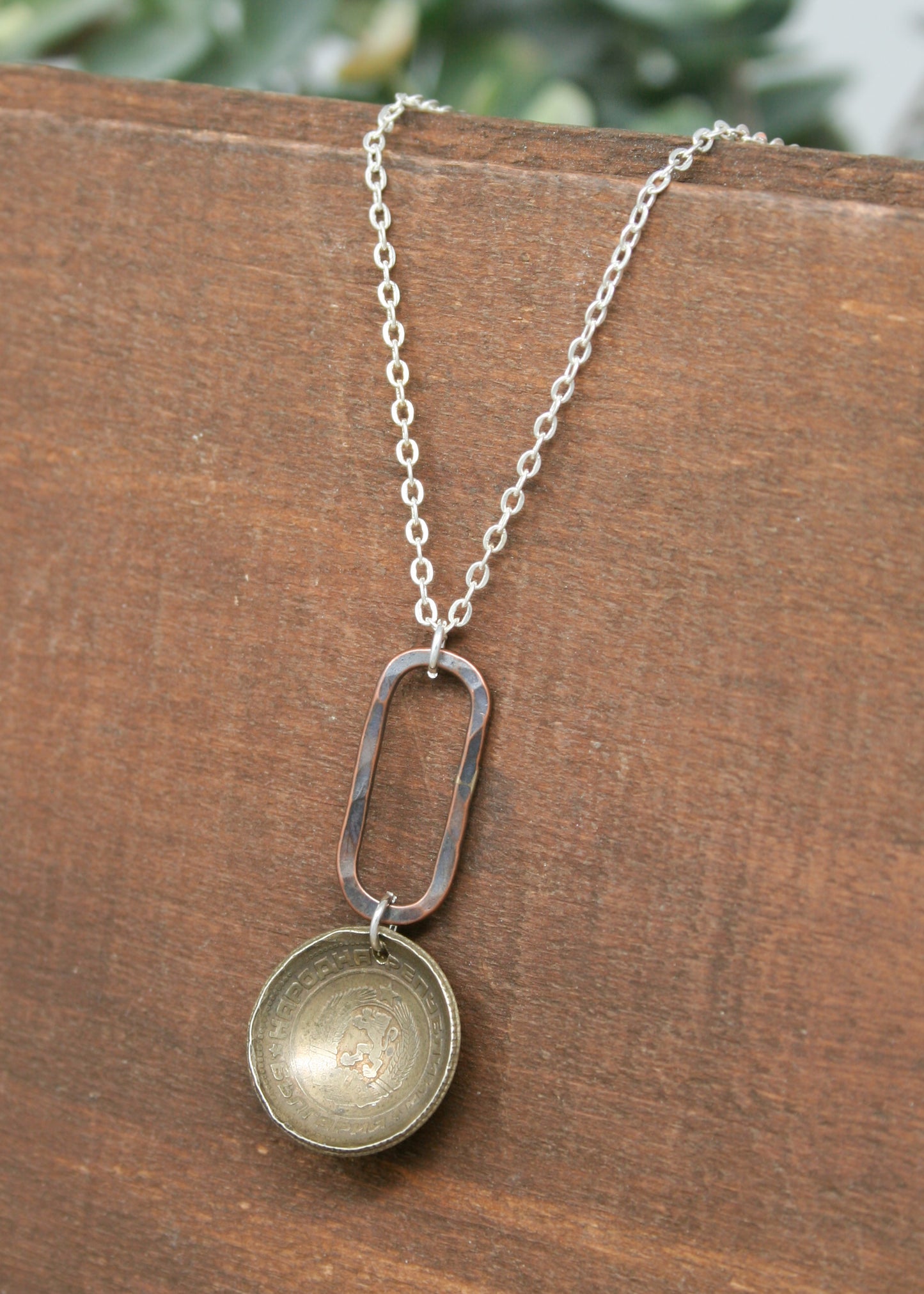 a silver necklace with a small metal object hanging from it