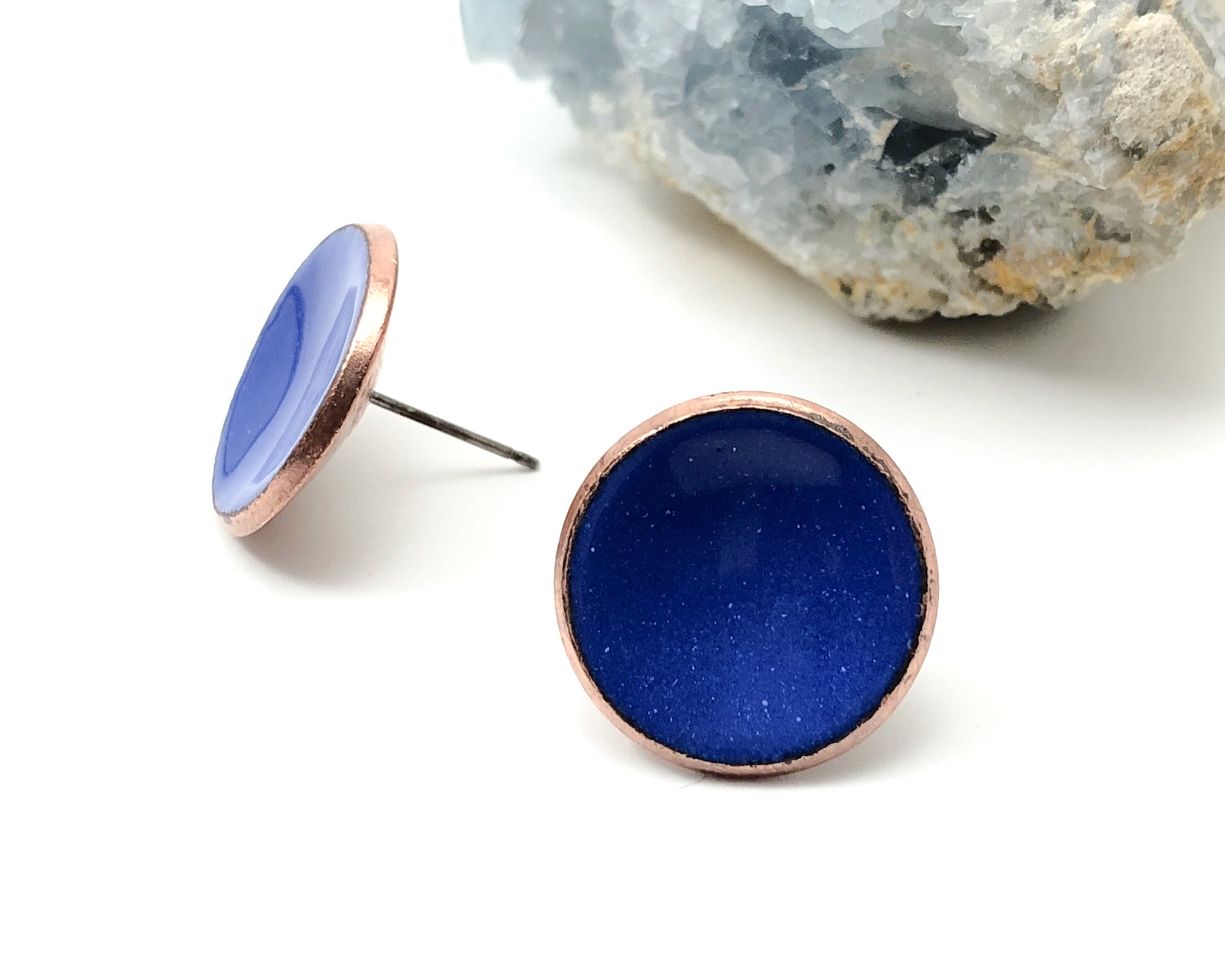 a pair of blue studs sitting next to a rock