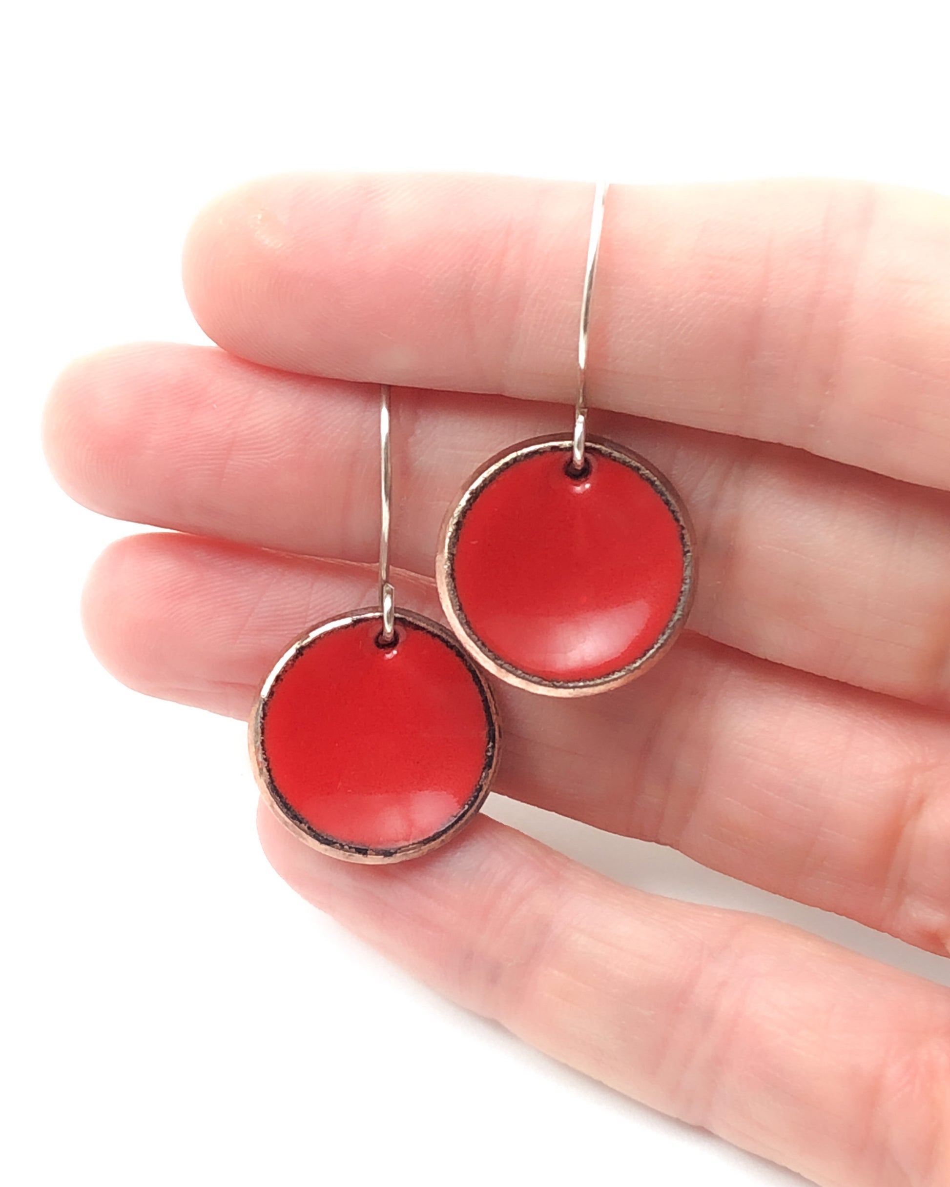 a hand holding a pair of red earrings