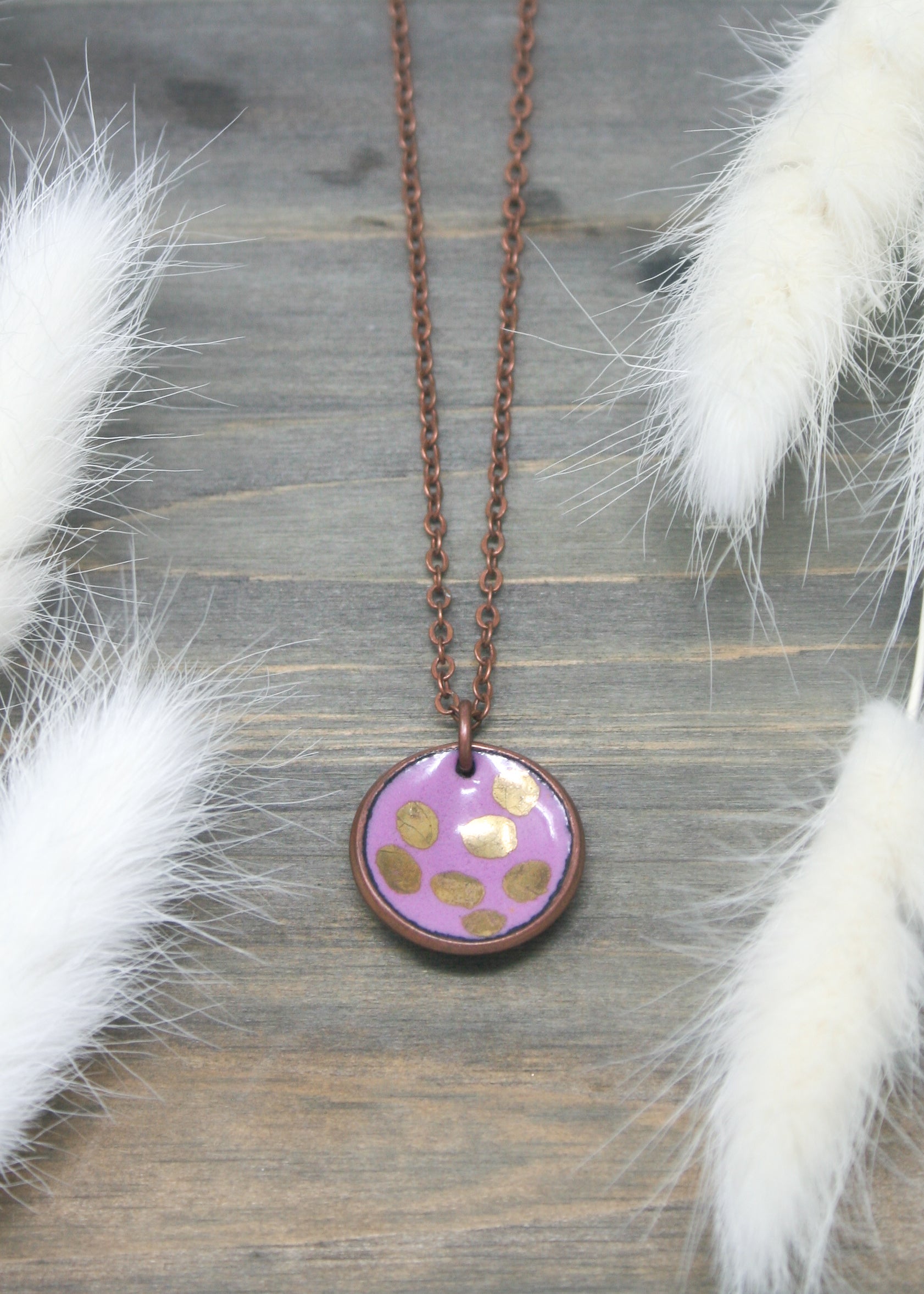 a necklace with a purple and gold donut on it