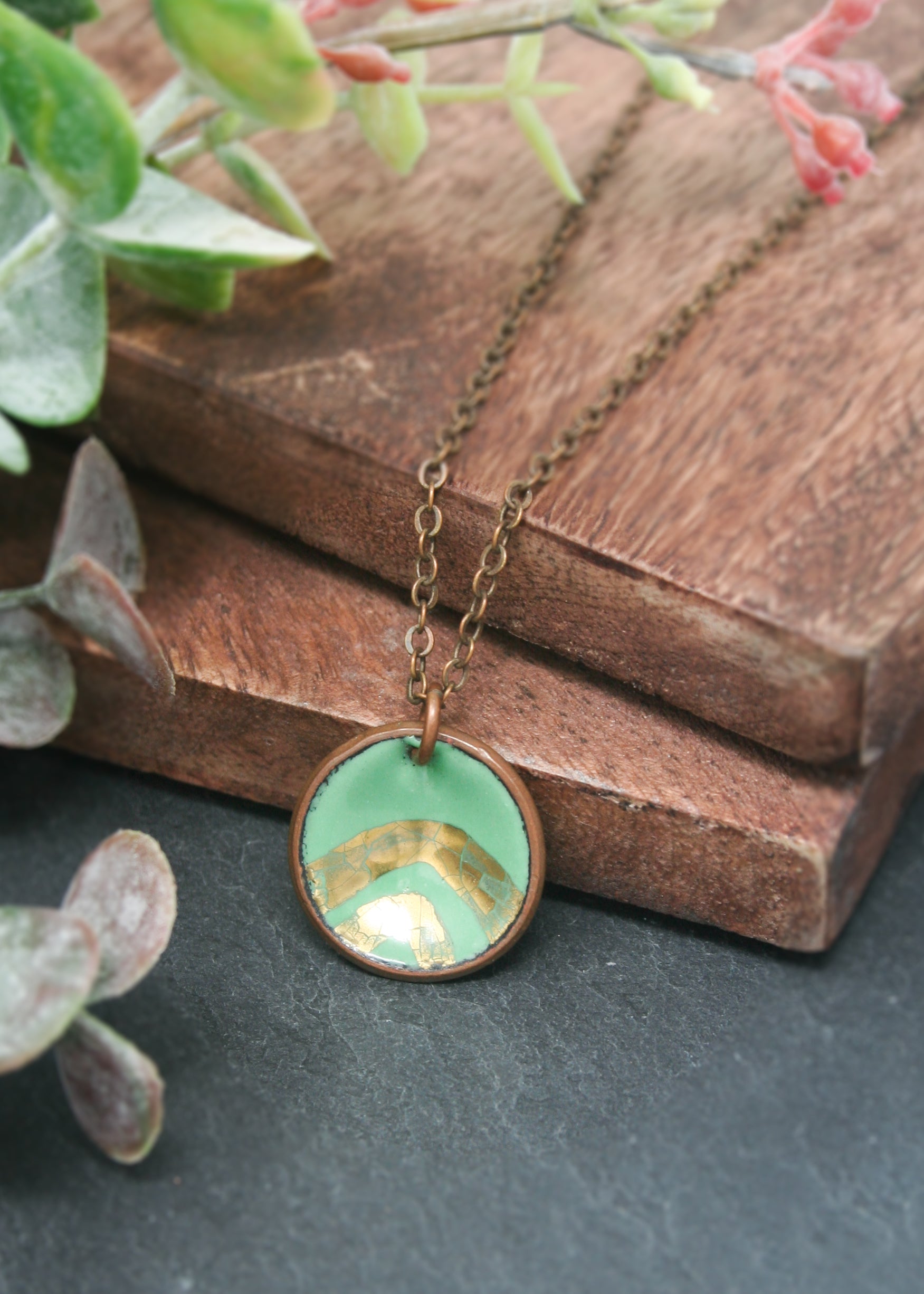 a necklace that has a small green bowl inside of it