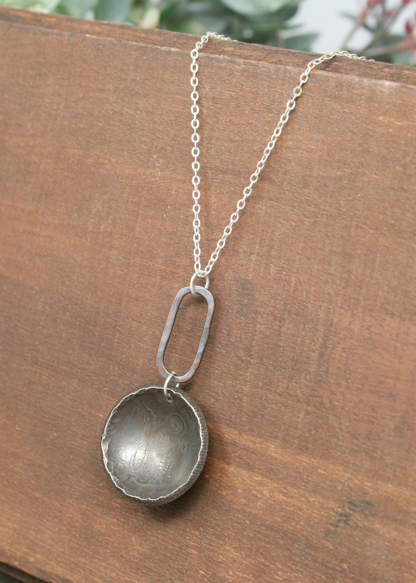a silver necklace with a small metal object hanging from it