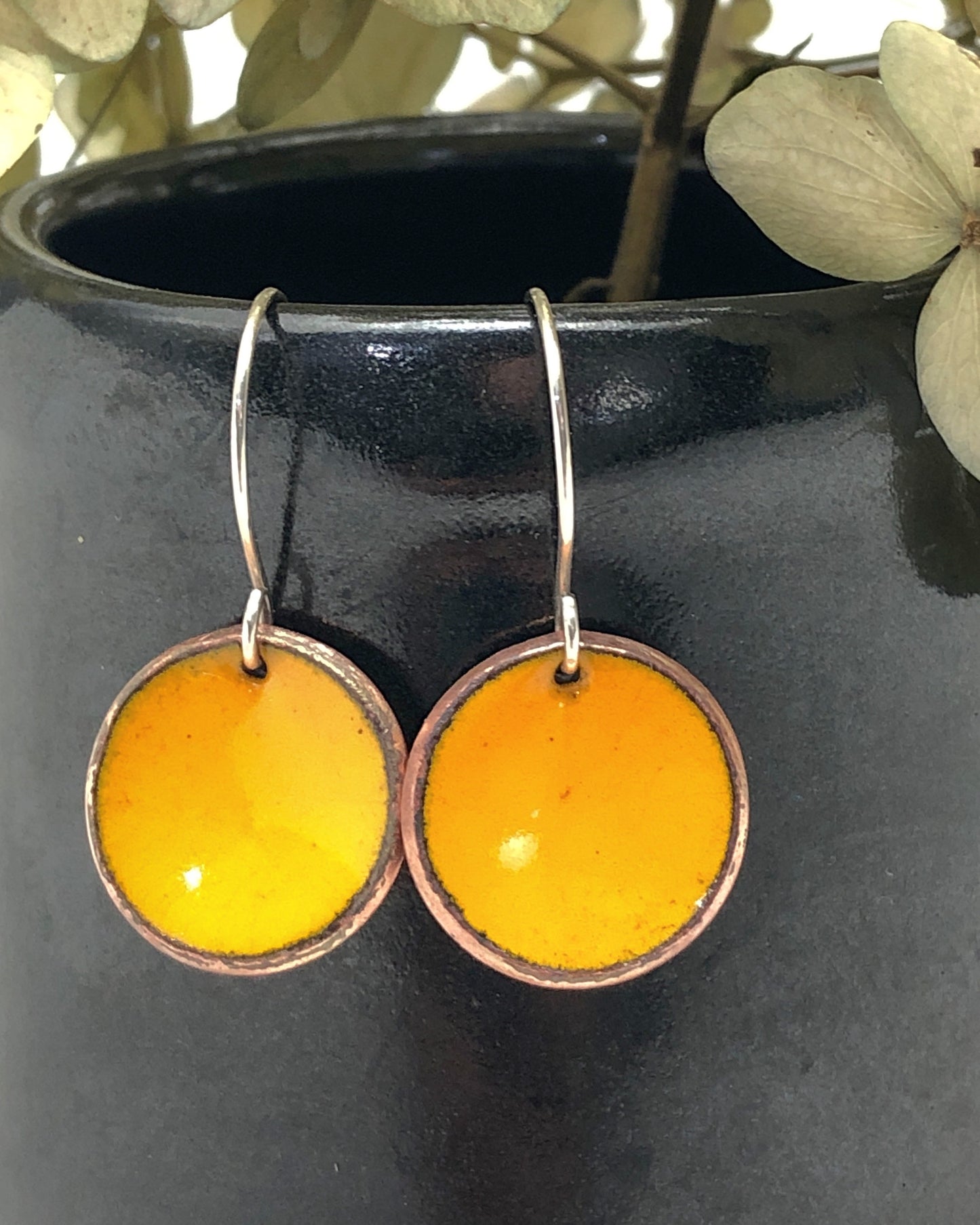 a pair of yellow earrings sitting on top of a vase