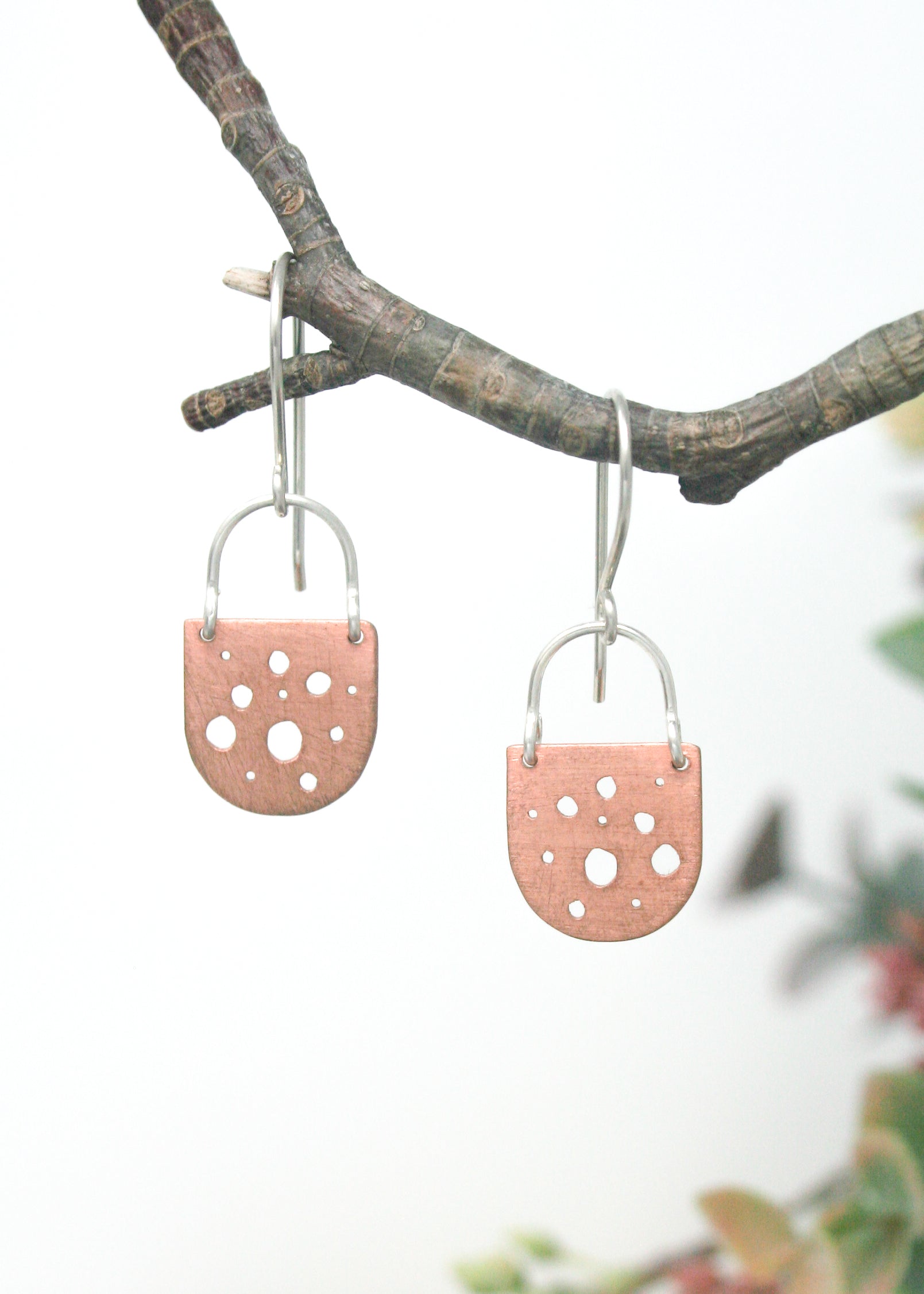 a pair of earrings hanging from a tree branch