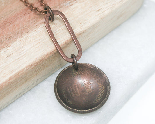 a necklace with a metal ball hanging from a chain