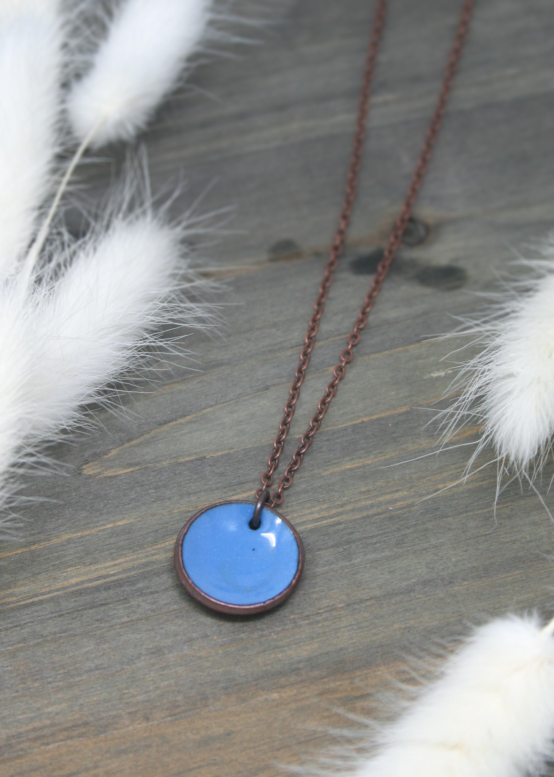 a necklace with a blue disc on a chain